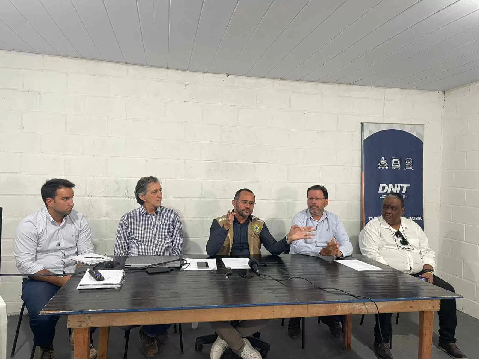 O Departamento Nacional de Infraestrutura de Transportes (DNIT) apresentou os detalhes do cronograma das obras relacionadas à Travessia Urbana de Juazeiro (BA), incluindo as intervenções na ponte Presidente Dutra. De acordo com o superintendente do DNIT na Bahia, Roberto Alcântara, as obras na ponte já começaram, focando inicialmente em limpeza e preparativos. As intervenções propriamente ditas terão início na alça de descida da ponte, no sentido Petrolina (PE) para Juazeiro (BA). O objetivo principal das obras é ampliar as alças da ponte, garantindo maior segurança e fluidez para carretas e caminhões que transitam pelo local. Após a conclusão da alça de descida, os trabalhos seguirão para a alça de subida no sentido inverso, Juazeiro (BA) para Petrolina (PE). O DNIT assegurou que não haverá interrupções no tráfego da ponte durante as obras. A previsão é de que o alargamento das alças seja concluído até o final de fevereiro ou início de março. Além disso, as obras completas da Travessia Urbana de Juazeiro estão programadas para serem finalizadas em julho de 2026. O projeto inclui intervenções de esgotamento sanitário e outros fatores necessários para o andamento dos serviços. As obras representam um passo importante para a infraestrutura da região, buscando atender à crescente demanda por transporte de cargas e melhorar a mobilidade entre Juazeiro e Petrolina.